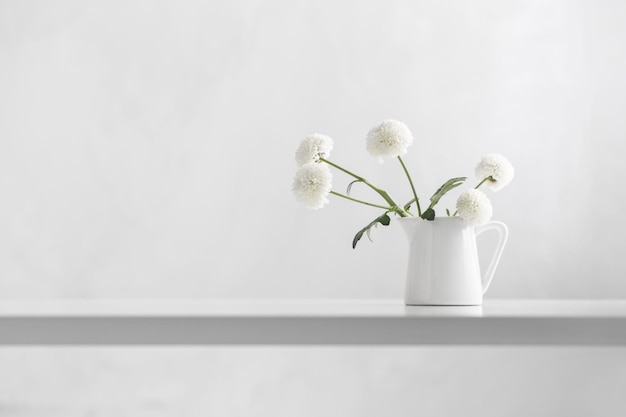 Weiße Chrysanthemen im Krug auf weißem Hintergrund