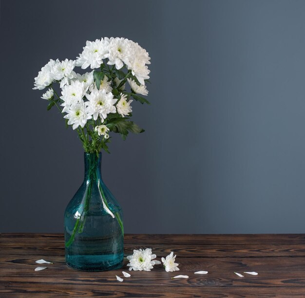 Weiße Chrysanthemen in Glasvase auf Holzhintergrund