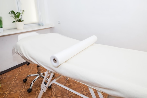 Weiße Couch in einem Massagesalon oder einem Schönheitssalon. Massageliege mit einer Rolle Einweglaken.