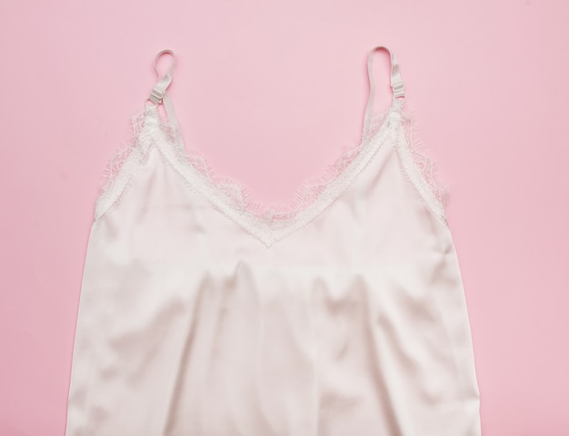 Weiße Damenunterwäsche aus Seidenspitze. Auf einem rosa Hintergrund.