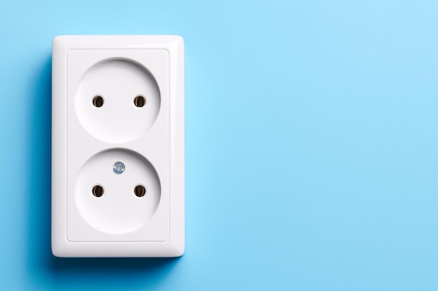 Weiße Doppelsteckdose auf blauem Hintergrund isoliert Elektrisches Beleuchtungskonzept