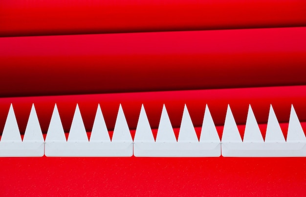 Weiße, dreieckige, spitze Zähne, die in einer roten Reihe auf einem rot gestreiften Hintergrund herausragen