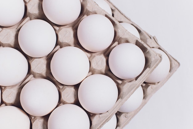 Weiße Eier einer Henne in der harmlosen, Pappverpackung auf Weiß