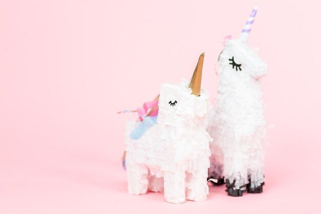 Weiße Einhorn-Pinata auf rosa Hintergrund.