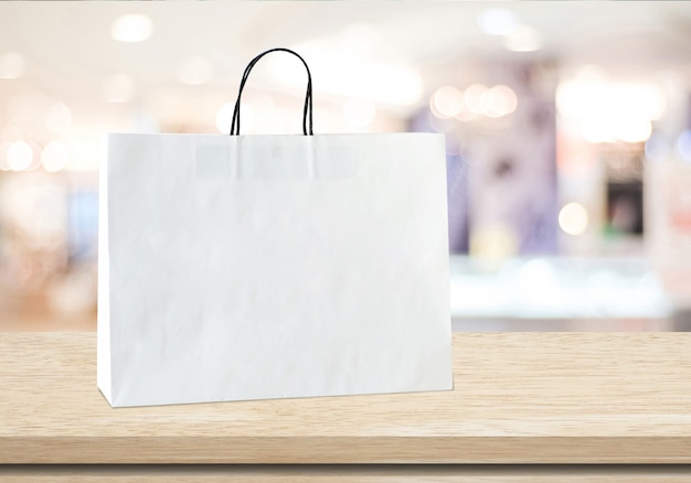 Weiße Einkaufstasche auf Tabelle über unscharfem Speicherhintergrund