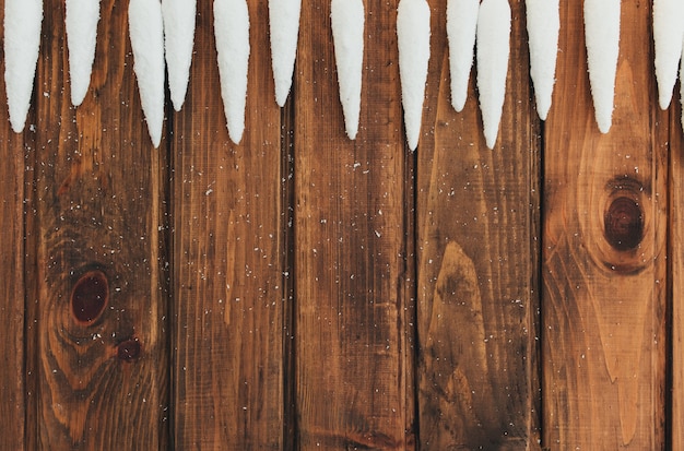 Weiße Eiszapfen auf altem braunem Holz.