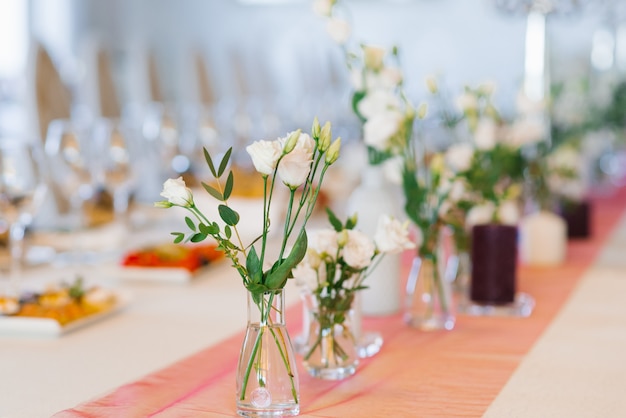 Weiße Eustomablumen stehen in den Glasvasen auf einer festlichen Tabelle an einer Hochzeit