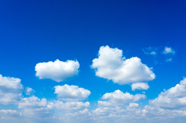 Weiße flaumige Wolken mit Regenbogen im blauen Himmel