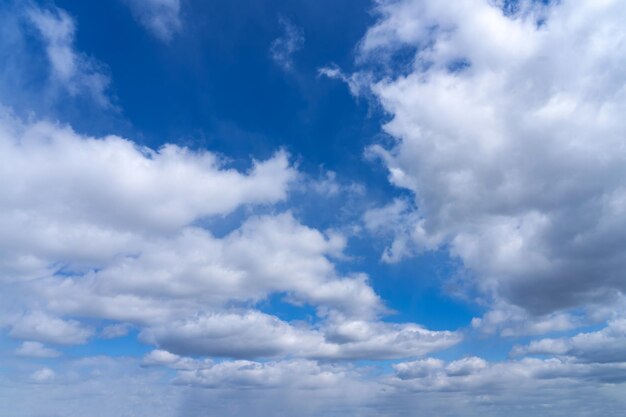 Weiße, flauschige Wolken, die sich vor einem schwarzen Hintergrund und einem blauen Himmel abheben