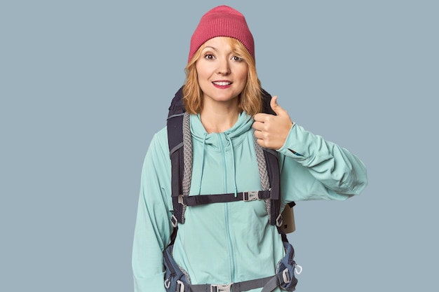 Weiße Frau mittleren Alters mit Wanderausrüstung lächelt und hebt den Daumen nach oben