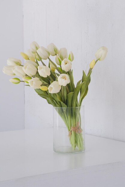 Weiße Frühlings-Tulpen in einer Vase auf einem weißen Tisch-Mockup für die Ausstellung von Werken