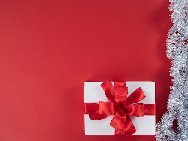 Weiße Geschenkbox mit rotem Band auf rotem Hintergrund