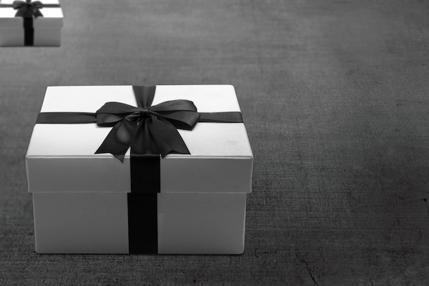 Weiße Geschenkbox mit schwarzem Band auf dem Boden. Black Friday-Konzept