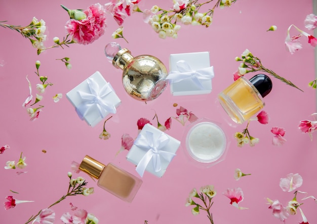 Weiße Geschenkboxen mit Kosmetik- und Chamelauciumblumen auf rosa Wand