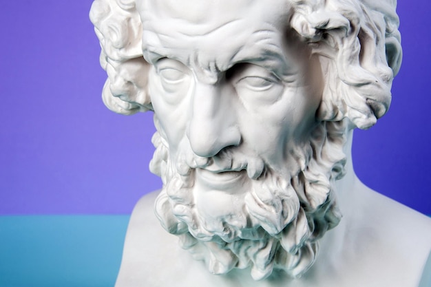 Weiße Gipskopie der antiken Homer-Statue für Künstler auf blauem Grund. Gipsskulptur des Gesichtes des Mannes.