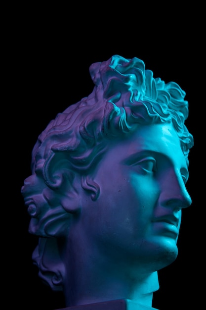 Weiße Gipskopie der antiken Statue des Apollongottes des Sonnenkopfes für Künstler einzeln auf schwarzem Hintergrund. Gipsskulptur des Gesichtes des Mannes. Blau und lila getönt.