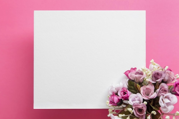 Foto weiße grußkarte auf rosa hintergrund mit blumenstrauß flaches design