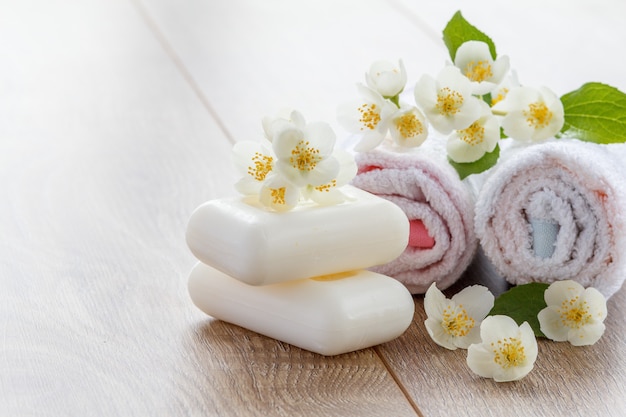 Weiße Handtücher und Seife für Badezimmerverfahren mit Jasminblüten auf Holzbrettern mit Kopierraum. Spa-Produkte und Zubehör