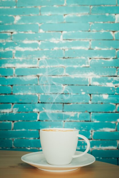 Weiße heiße Kaffeetasse auf Holztisch auf grünem Hintergrund