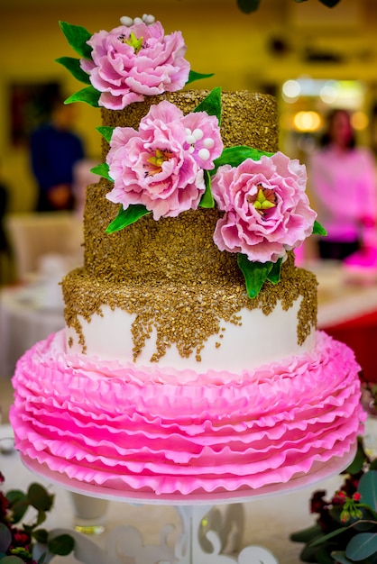 Weiße Hochzeitstorte verziert mit rosa Zuckerpfingstrosen. Die Zusammensetzung der Blumen