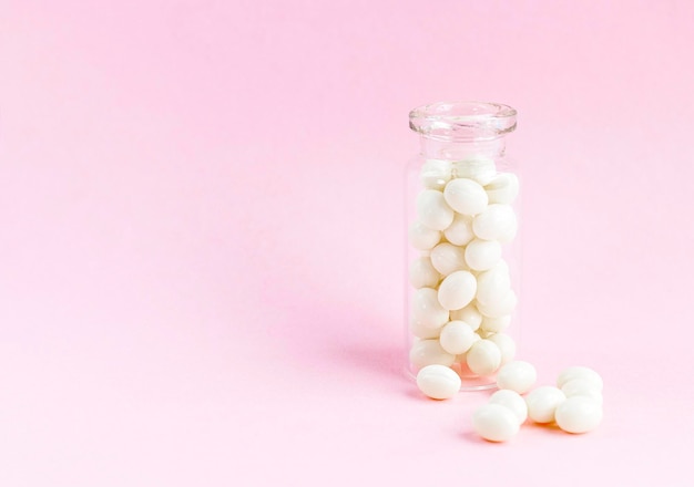 Weiße homöopathische Kapseln in einer Glasflasche auf rosa Hintergrund Alternative Medizin Copyspace für Text
