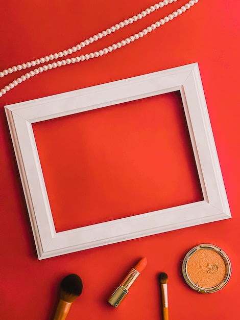Weiße horizontale Kunstrahmen-Make-up-Produkte und Perlenschmuck auf orangefarbenem Hintergrund als Flatlay-Design-Kunstdruck oder Fotoalbum