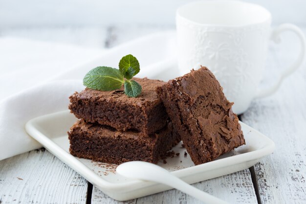 Weiße isolierte Wand mit hausgemachten dunklen Schokoladenbrownies und Minze köstlichen bitteren süßen und Fudge. Brownie ist eine Art von Schokoladenkuchen. Vintage Ton.