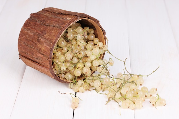 Weiße Johannisbeeren im Holzbecher auf Holzhintergrund