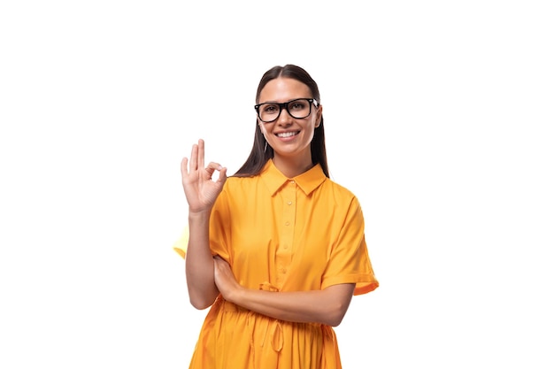 Weiße junge Frau mit schwarzen glatten Haaren trägt eine Brille und ein gelbes Kleid