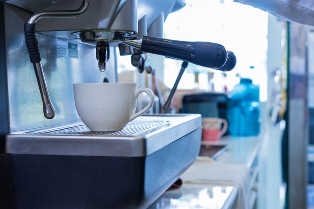 Weiße Kaffeetasse auf Kaffeemaschine.