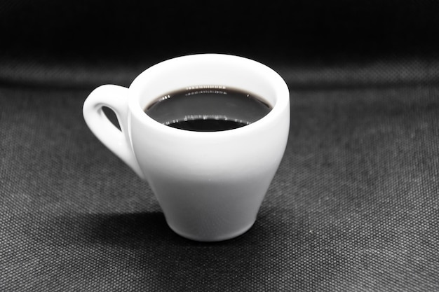 Weiße Kaffeetasse auf schwarzem Hintergrund.