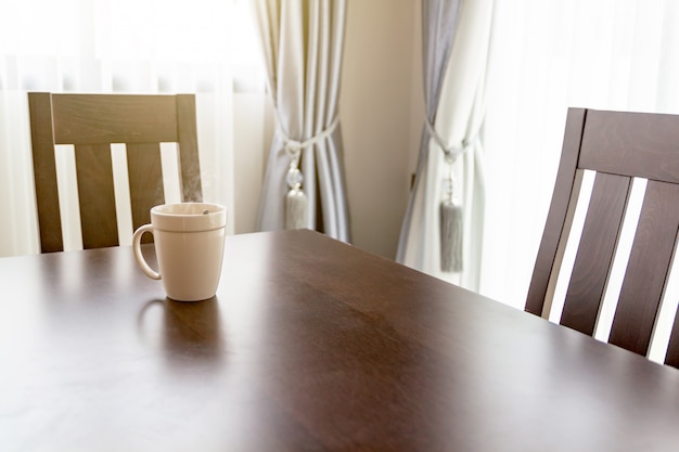 Weiße Kaffeetasse morgens gesetzt auf einen hölzernen Schreibtisch.