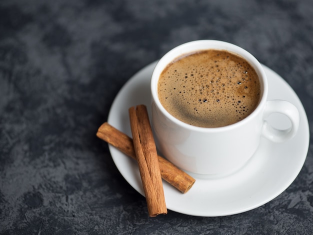 Weiße Kaffeetasse und Hühnerscheiben auf dunkler Steinoberfläche