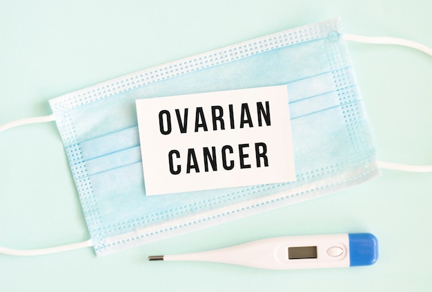 Weiße Karte mit der Aufschrift OVARIAN CANCER auf einer medizinischen Schutzmaske