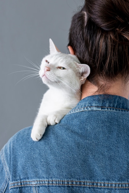 Weiße Katze, die auf Inhaberschulter sitzt