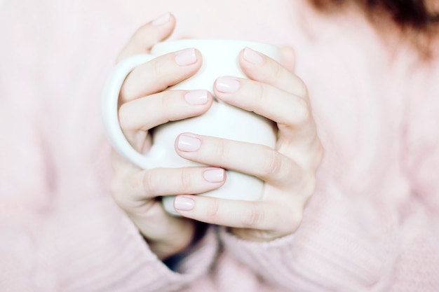 weiße Keramikkaffeetasse in der Hand der Frau