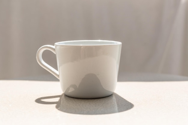 Weiße keramische Kaffeetasse auf einem keramischen Außentisch an einem sonnigen Tag