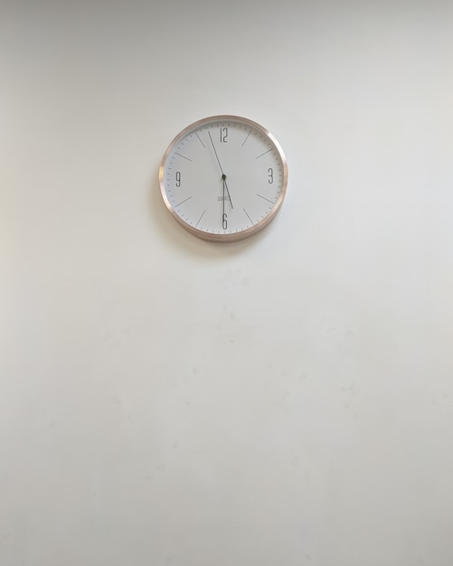 Weiße klassische runde Uhr an der grauen Wand Textfreiraum keine Leute Büroinnenraum-Minimalismus-Design