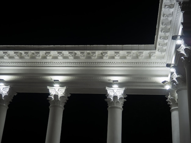 Weiße Kolonnade im Dunkeln Weiße Säulen im Licht der Scheinwerfer Straßendekorationsarchitektur Element des architektonischen Ensembles im Stadtpark