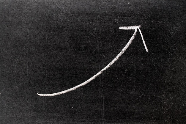 Foto weiße kreidehandzeichnung in aufwärtspfeilform auf tafelhintergrund