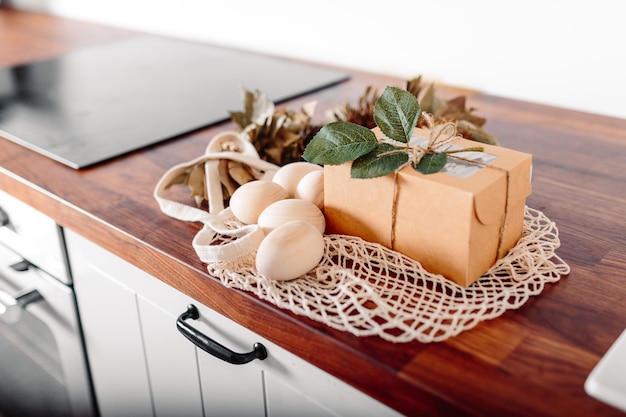 Foto weiße küche mit eiern und geschenkbox fröhliche osterkarte mit holzeiern mesh-shopper mit eiern