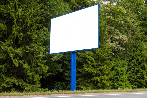 Weiße leere Anschlagtafel gegen grünen Wald entlang Straße