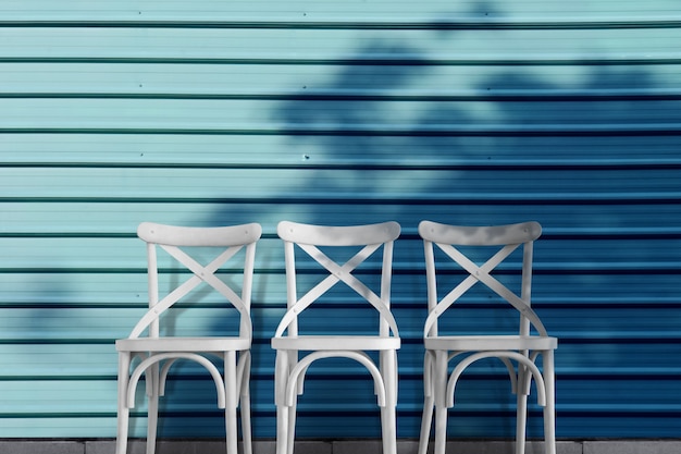 Weiße leere Stühle an der blauen Wand