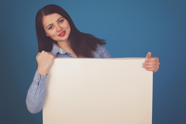 Weiße Leinwand wird von einer Frau vor blauem Hintergrund gehalten