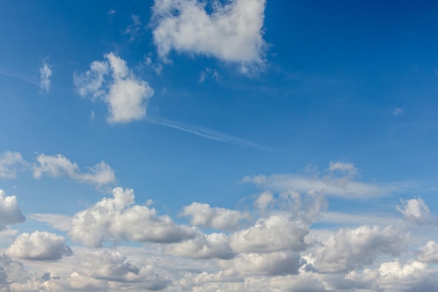 Weiße lockige Wolken in verschiedenen Formen am blauen Himmel bei sonnigem Wetter_