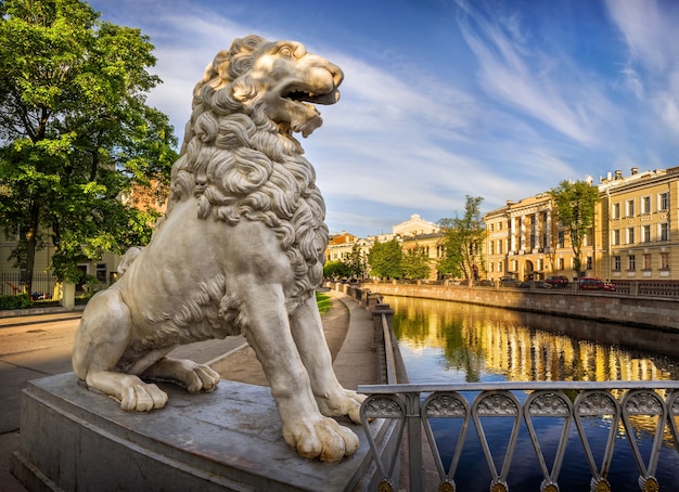 Weiße Löwenstatue auf der Brücke und Häuser entlang des Kanals im Morgenlicht in St. Petersburg