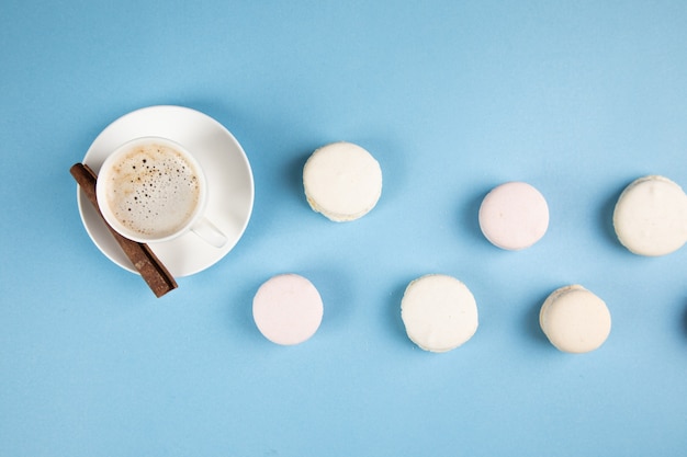 Weiße Macarons und Kaffee mit Zimt auf einer blauen Oberfläche