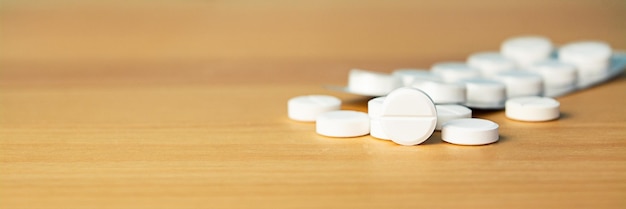 Weiße medizinische Pillen auf dem Tisch verstreut Seitenansicht von oben Kopierbereich Banner