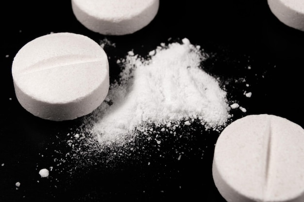 Weiße medizinische Pillen und Tabletten auf schwarzem Hintergrund Nahaufnahmefoto von medizinischen Präparaten mit Kopierbereich