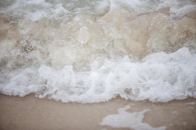 Weiße Meereswellen sprühen mit Sandstrand